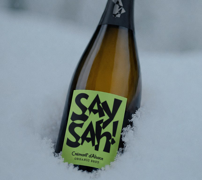 A bottle of Saysah Organic Brut standing in fresh snow