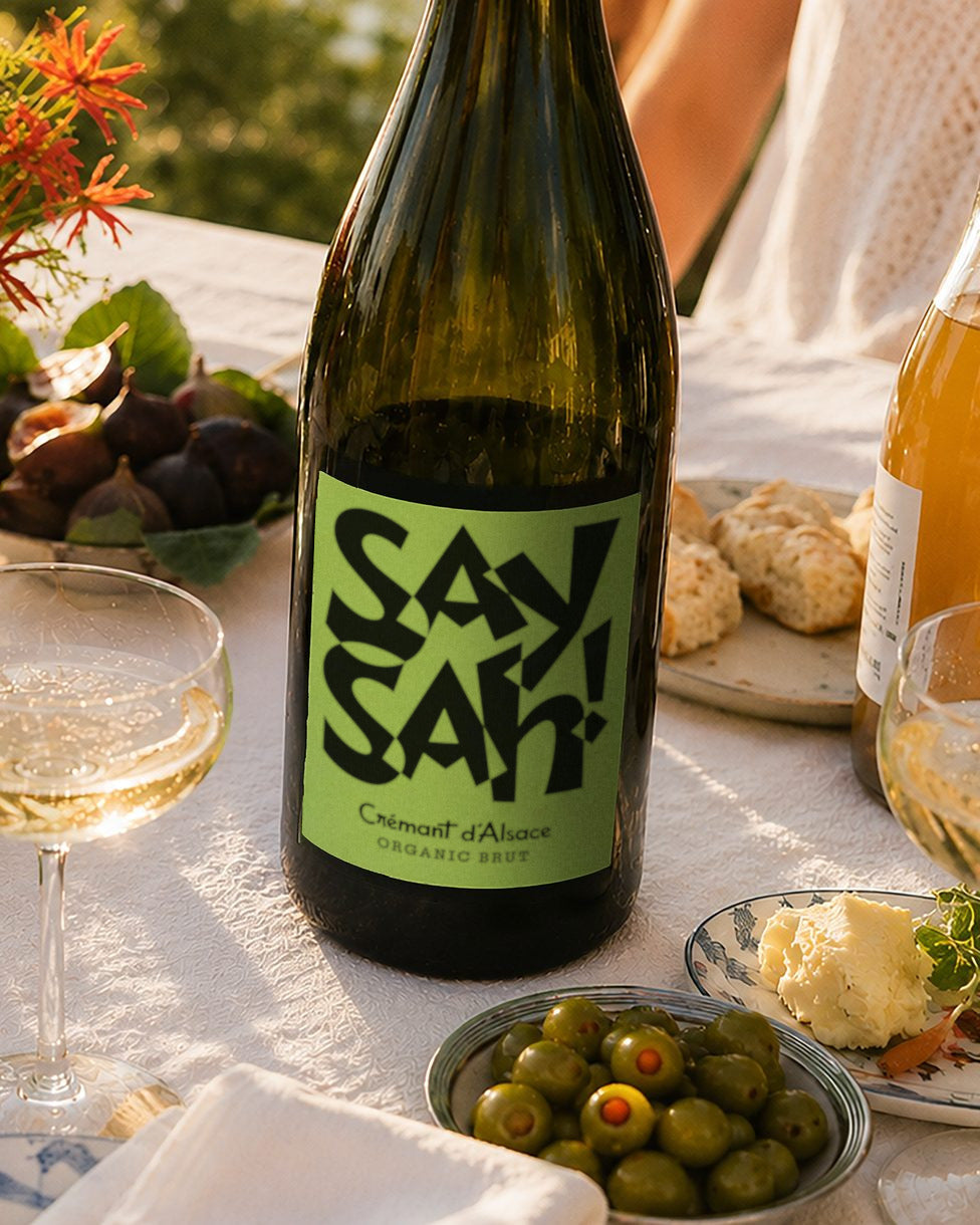 A summer table with a bottle of Saysah Organic Brut, oysters, peaches and glasses